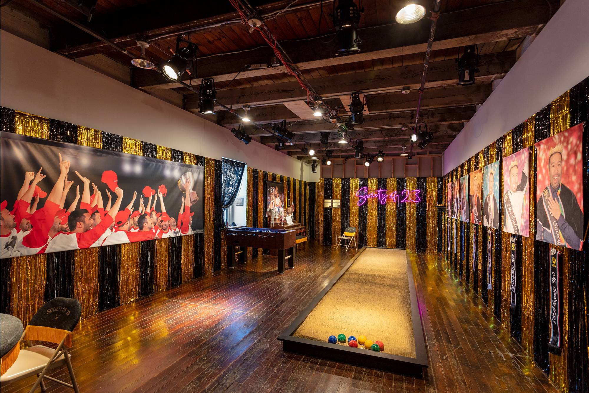 Art gallery filled with celebratory glittering sports memorabilia, portrait photography, games and tinsel.